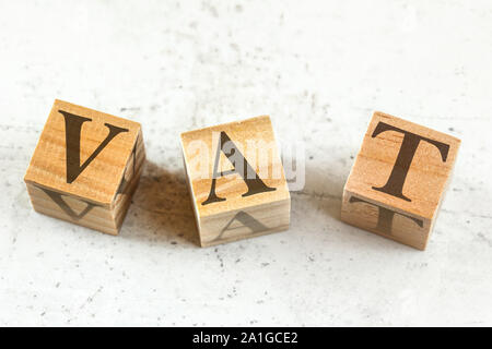 Three wooden cubes with letters VAT stands for Value Added Tax on white board. Stock Photo