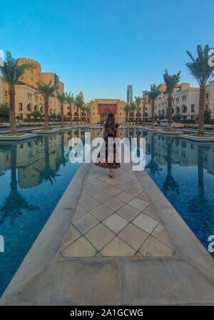 Silhouette of young beautiful woman on the road along swimming pool near Downtown Burj Dubai district. Stock Photo