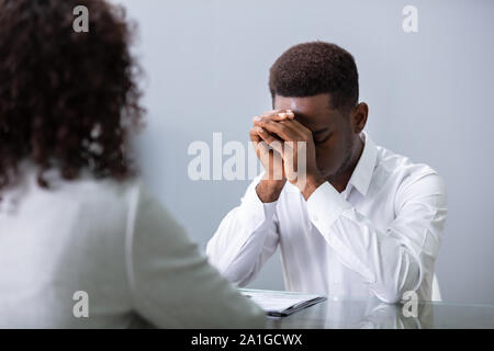 Stressed Young Business Man Holding His Head At Interview In Office Stock Photo