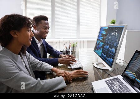 Stock Market Broker Analyzing Graphs On Computer In Office Stock Photo