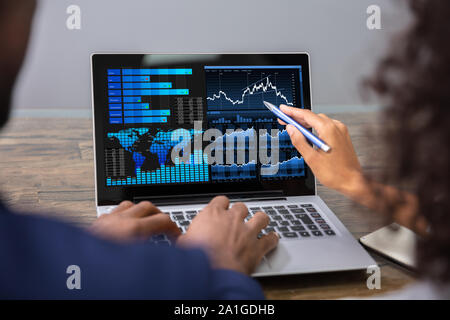 Two Businesspeople Analyzing Financial Graph On Laptop Stock Photo