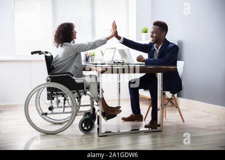 Disabled Businesswoman Giving High Five To His Partner In Office Stock Photo