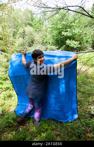 person camping or outdoors hangs up a blue tarp to dry in the sun Stock Photo