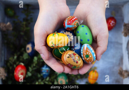Child holding a handful of wooden colorful Easter eggs Stock Photo