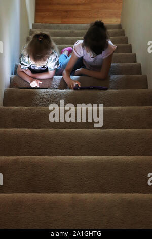 Two children playing on their electronic devices