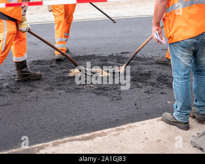 Group of people workers wearing special protection and safety orange costumes posing asphalt in Dutch city central square street Stock Photo