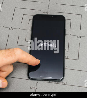 Paris, France - Sep 12, 2019: View from above of man pressing touchscreen on latest iPhone 11 Pro with Le Monde newspaper app working Stock Photo