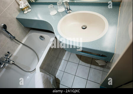 View from above of interior of modern three star hotel with sink, chrome water tap, two glasses and defocused shampoo in the corner Stock Photo