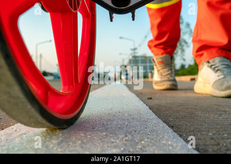 Close up measuring road distances with a measuring wheel Stock Photo