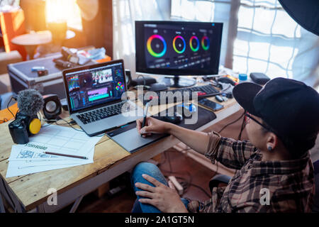 The freelance editor working in the house studio using laptop editing video footage Stock Photo