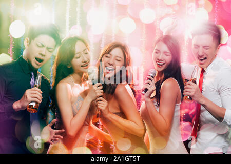 young group holding microphone and singing at karaoke Stock Photo