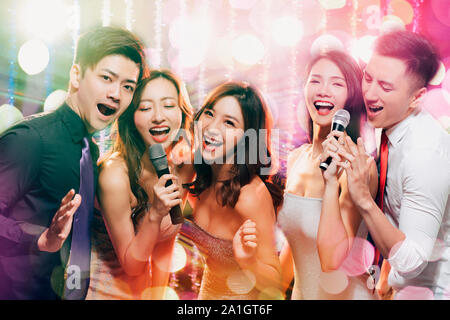 young group holding microphone and singing at karaoke Stock Photo