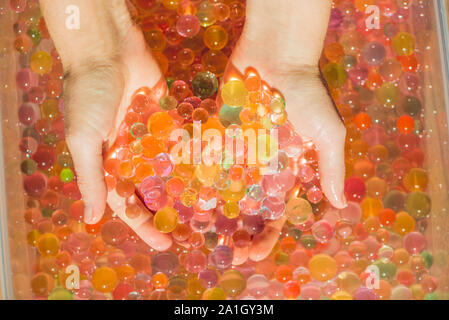 Colored balls of water beads, hydrogel in in hands. Sensory experiences. Stock Photo
