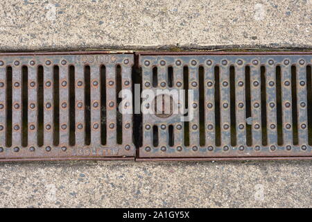 Slightly rusty iron mesh cover of roadside stormwater drain. Stock Photo