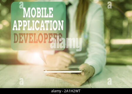Writing note showing Mobile Application Developers. Business concept for create software for devices like app store Female business person sitting by Stock Photo