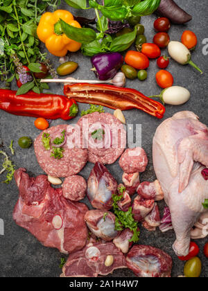 Different types of raw meat: beef, chicken, lamb, gilbert, pork, herbs, lettuce, garlic cherry tomatoes bell pepper greenery close up Stock Photo