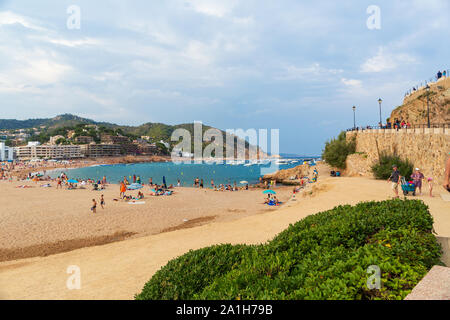 TOSSA DE MAR, SPAIN - AUGUST 7, 2019: View of the central city beach during the high summer season. Sunlight, greenery and an ancient fortress in the Stock Photo