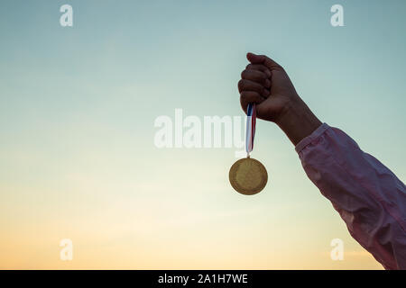 Hand holding a gold coin held up high and victory. Stock Photo