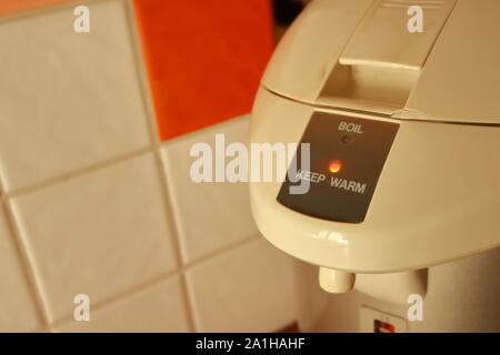 Closeup electric boiler pot in the kitchen under sunlight, focus on illuminated lamp of keep warm position, friendly concept Stock Photo