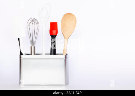 Assortment of kitchenware and cooking tools in a square silver colored metal box with copy space on white background