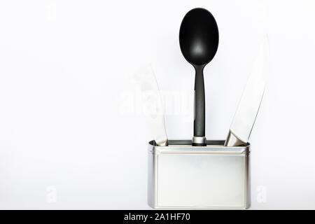 Assortment of kitchenware and cooking tools in a square silver colored metal box with copy space on white background Stock Photo
