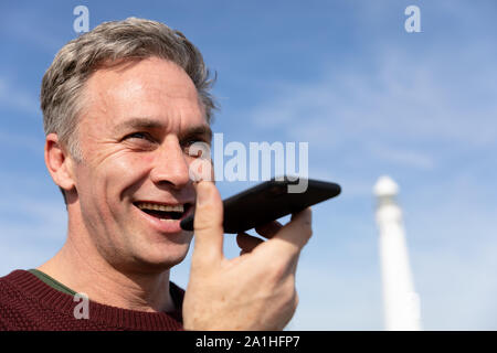 Man standing near lighthouse using smartphone Stock Photo