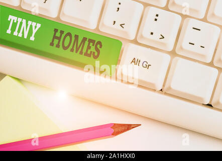 Conceptual hand writing showing Tiny Homes. Concept meaning houses contain one room only or two and small entrance Cheap White pc keyboard with note p Stock Photo