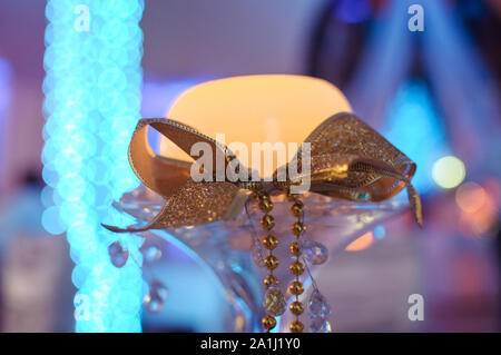 Close-up of illuminated candle with golden ribbon and fairy lights Stock Photo