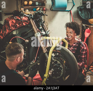 Mechanic and his helper repairing a motorcycle in a workshop Stock Photo
