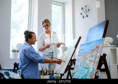 Creative painter and her protege working in a studio Stock Photo