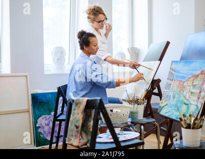 Creative painter and her protege working in a studio Stock Photo