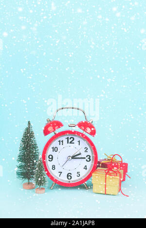alarm clock next to christmas tree and gifts on blue background Stock Photo