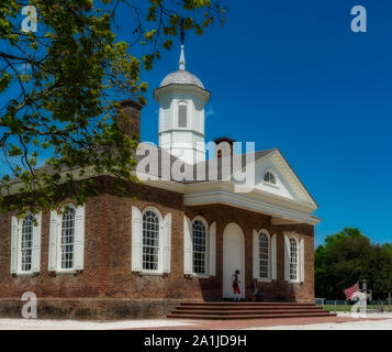Williamsburg courthouse on sunny day with man in red pants standing in front of doorway Stock Photo