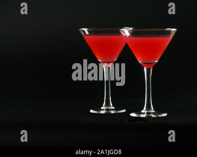 Classic Bacardi alcoholic cocktail of bright red color from white rum, lime juice and grenadine, in two conical cocktail glass on a dark background Stock Photo