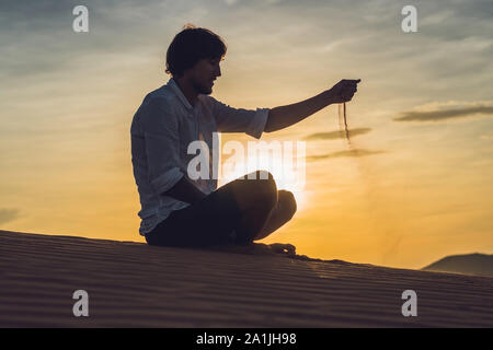 A man is pouring sand in the desert. Sand through the fingers of the concept Stock Photo