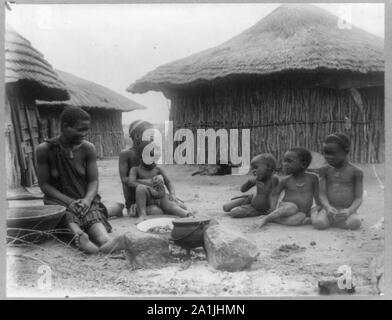 Native woman and five children in front of huts near Bulawayo, Rhodesia, Africa Stock Photo