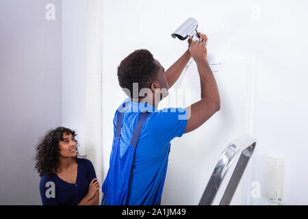 Technician Installing Security Camera System At Home Stock Photo
