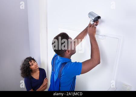 Technician Installing Security Camera System At Home Stock Photo