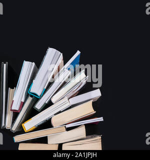 a series of books arranged like a fan on a black surface seen from above Stock Photo