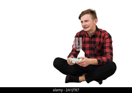 Angry teenage boy playing video games isolated over white background. Upset adolescent guy seadted on the floor holding a joystick console try to win, Stock Photo