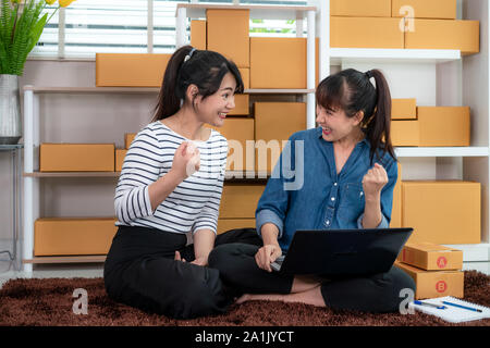 Charming two Asian teenager owner business woman work sitting on floor for online shopping, looking and excited in order at laptop and with office equ Stock Photo