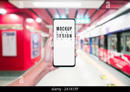 Mockup of hand using mobile phone with copy space blank screen for your advertisement with blurred view of red subway, internet social media technolog Stock Photo
