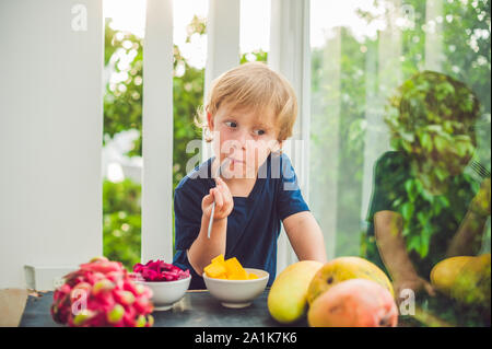 Little cute boy eating mango on the terrace Stock Photo