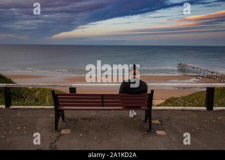 One lonely man sat on the beach looking out to sea Stock Photo