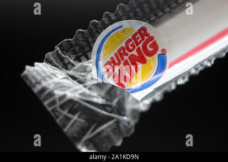 Plastic straw plastic cellophane wrapper from Burger King chain of hamburger fast food restaurant, isolated on black background, close-up Stock Photo