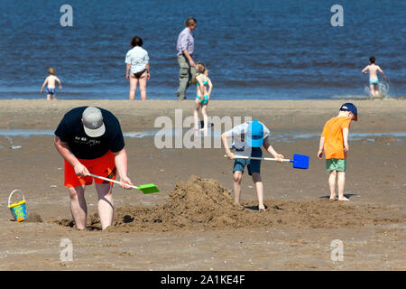 SCHEVENINGEN - Father and son digging holes in the sand Stock Photo