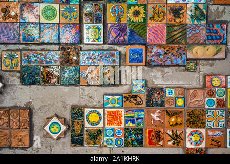 Riomaggiore, Cinque Terre, Italy - August 17, 2019: Decoration of miniature embossed tiles with color patterns for folk motifs. Image of fish, gulls, Stock Photo