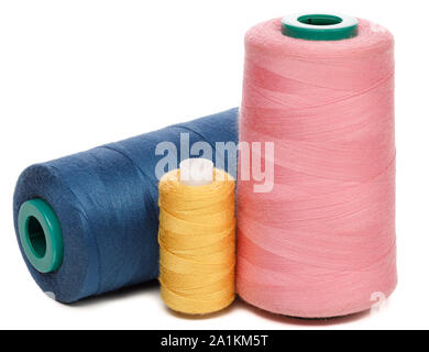 Group of spools of pink yellow and blue synthetic or cotton threads isolated on white background used for weaving in textile manufacturing Stock Photo