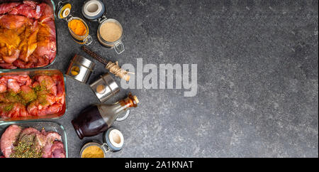 Marinating raw meat in different spices, herbs and marinades, with soy sauce and oil on grey concrete background Stock Photo