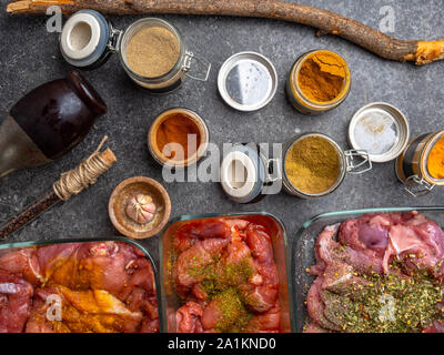 Marinating raw meat in different spices, herbs and marinades, with soy sauce and oil on grey concrete background Stock Photo